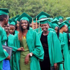 Group of smiling young people in green graduation gowns