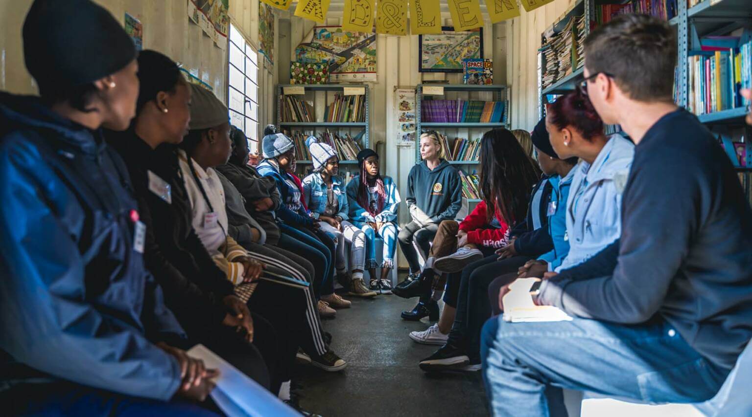 actor Charlize Theron with a group of kids in a library